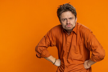 Obraz premium Upset frustrated annoyed man raising hands in indignant expression, quarreling asking reason of conflict problem, why such stubborn. Irritated guy isolated on orange background indoors. Copy-space