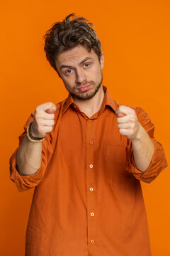 Greedy avaricious Caucasian man showing fig negative gesture you don't get it anyway. Rapacious avaricious acquisitive. Body language. Refusal fig sign. Young guy isolated on orange background indoor