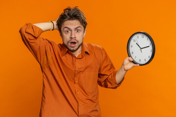 Caucasian man with anxiety checking time on clock, running late to work, being in delay, deadline....