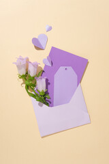Top view of few pieces of paper with copy space and flowers contained inside an envelope. Paper cut in heart shaped decorated. Purple colored props