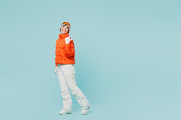 Full body young skier woman wear warm padded windbreaker jacket hat ski goggles mask point finger...