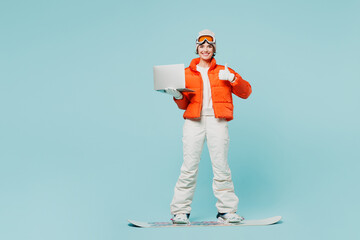 Full body young IT woman wear windbreaker jacket hat ski goggles mask snowboarding use laptop pc...