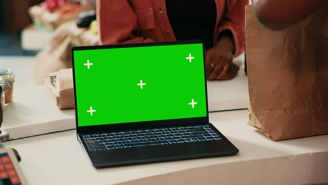 Greenscreen isolated display on laptop at farmers market, local vendor selling homegrown organic products at checkout. Woman buying fresh produce, blank chromakey copyspace template.