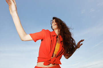 Sea Dance of Joy: Smiling woman in red clothes enjoying freedom and summer vacation on the sunny beach