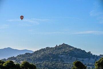 Hot Air Balloon Floating Above a Forested Hill