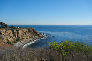Fototapeta na wymiar Breathtaking scenic and landscape view of coastline of Rancho Palos Verdes with vegetation and cliffs and beautiful bays overlooking ocean and coast in California on sunny blue sky day