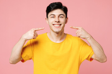 Young smiling happy Caucasian man he wearing yellow t-shirt casual clothes point index fingers on...