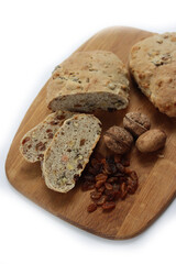 Homemade sliced Pan co' Santi from Tuscany (Italy) on wooden cutting board on white. Traditional sweet bread with raisins, almonds, walnuts and aniseed and Vinsanto