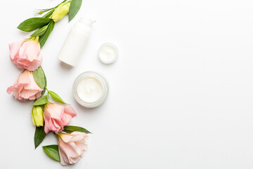 Composition with cosmetic products and beautiful roses on white background. Copy space, flat lay