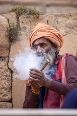 Indian holy sadhu smoking during the kumbh fair in traditional clothes.