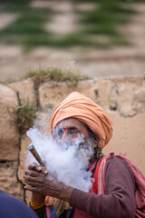 Indian holy sadhu smoking during the kumbh fair in traditional clothes.