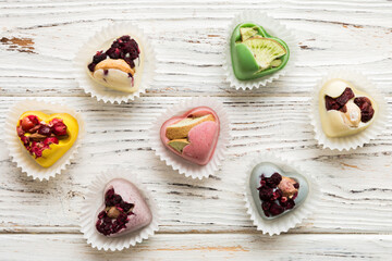 chocolate sweets in the form of a heart with fruits and nuts on a colored background. top view with space for text, holiday concept