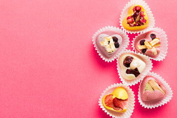 chocolate sweets in the form of a heart with fruits and nuts on a colored background. top view with space for text, holiday concept