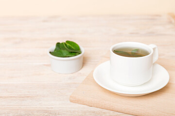 Cup of mint tea on table background. Green tea with fresh mint top view with copy space