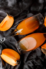 Glass with orange jelly and persimmon pieces on a gray background