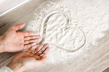 heart drawn on flour and women's hands, top view 