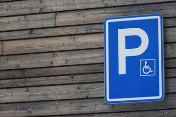 Reserved parking for disabled persons, handicapped symbol on wooden background.