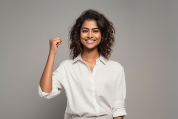Young smiling woman showing a cheering gesture with closed fist
