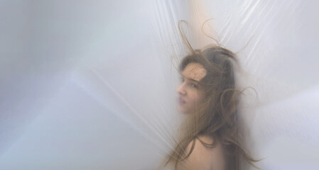 blurred, fuzzy image portrait of sensual young teasing woman, wild hair at the plastic film, moves...