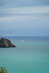 Fototapeta na wymiar Tiny sailboat on vast ocean expanse.