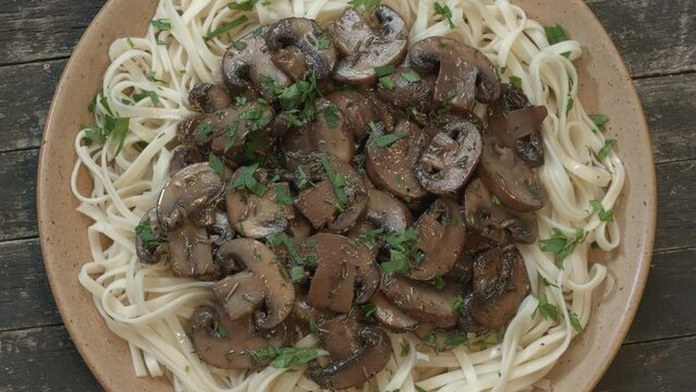 Top view of chow mein noodles with sauted champignon mushroom on top. Table spin.