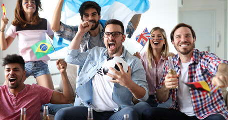 Soccer fans emotionally watching game in the living room.
