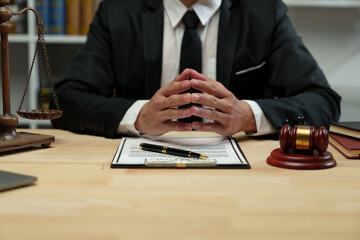A lawyer sits with his hands on his desk reading the legal code on a clipboard, studying the...