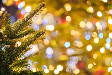 New year christmas tree branch with yellow flickering lights of garlands copy space background, merry christmas and happy new year mood, twinkling lights of street decorations, close up view to lights