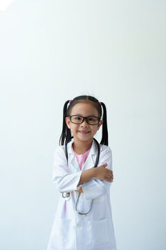 Smiling girl wearing glasses wearing a doctor's coat in medical practice stethoscope Standing with arms crossed and thinking. Treatment plan on white background. Career concept. Plan for the future.