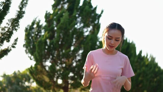 Image of health and healthy lifestyle of Asian woman in pink sportswear Preparing and stretching the muscles of the body and limbs for running in the park. Exercise outside the venue.