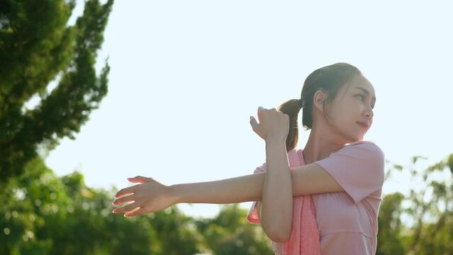 Image of health and healthy lifestyle of Asian woman in pink sportswear Preparing and stretching the muscles of the body and limbs for running in the park. Exercise outside the venue.