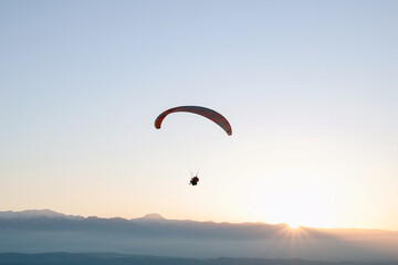 Paraglider flying over landscape sunset. Concept of extreme sport, taking adventure challenge.