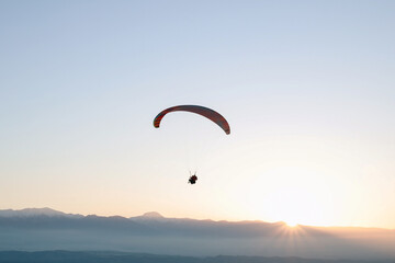 Paraglider flying over landscape sunset. Concept of extreme sport, taking adventure challenge.