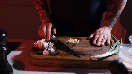 finely chopped garlic lies on a chopping board in front of the cook in the kitchen.