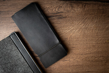 Handmade black wallet made of genuine leather on a wooden background. Close-up, top view.