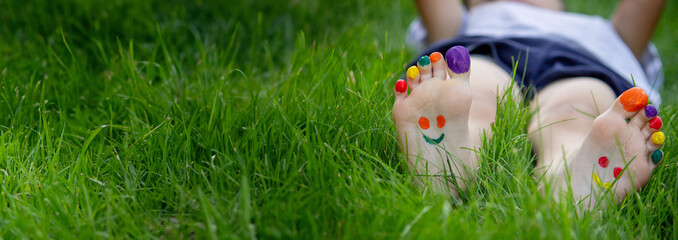 Children's legs with a pattern made of paints are smiling on the green grass