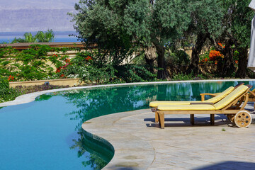 View of hotel Kempinski Ishtar Dead Sea in Jordan.View of pool with a sun lounger against the backdrop of old olive trees. Concept of tourism, recreation and treatment. Dead Sea, Jordan - May 23, 2011