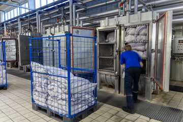 An employee loads bags of products into drying chamber for yarn.