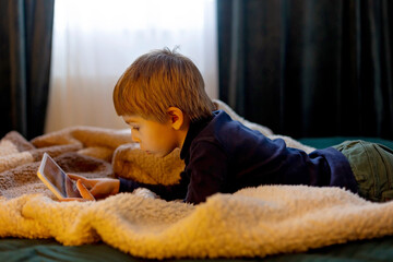 Child, school boy, reading book at home, cozy sunny bedroom