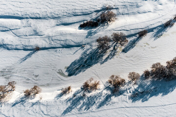 Winter landscape from the air with a view of a snow-covered river bed and many different footprints