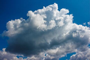 Large white cumulus cloud floating across the blue sky