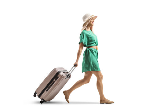 Young woman in a green dress walking and pulling a suitcase