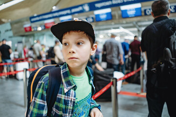 sad caucasian boy in airport with backpack and suitcase. Travelling concept