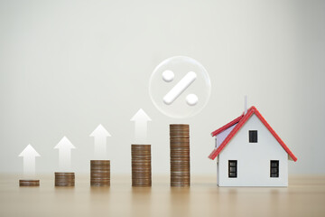 Percentage symbol for interest rate increase on coin pile and sample house. Interest rate hikes,...