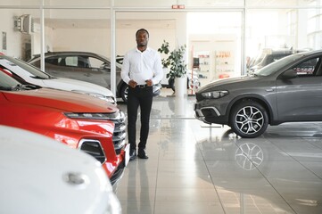 young african american car dealership principal standing in vehicle showroom