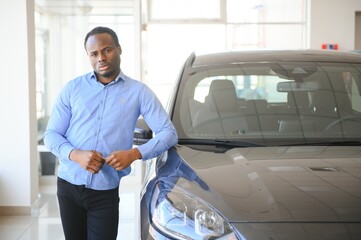 Handsome African man choosing a new car at the dealership