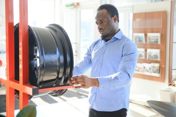 Obraz premium An African man buys car rims in an auto parts store