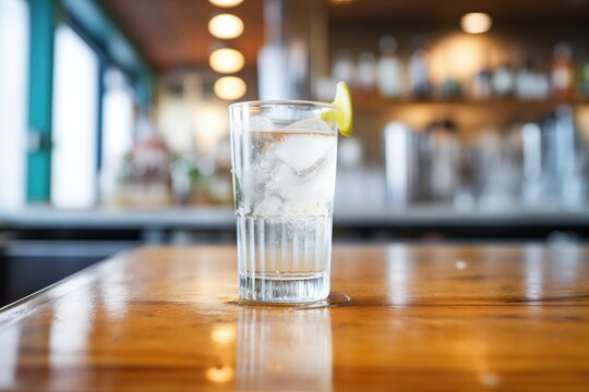 a clear glass filled with club soda and ice on a bar top