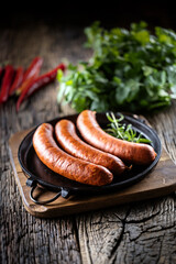 Pepper pork smoked sausages with rosemary in a cast iron pan