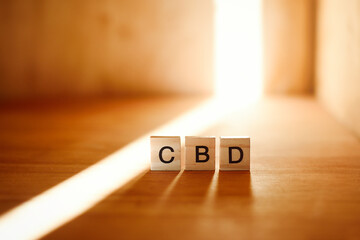 Cannabis CBD concept with wooden letters and natural light beam on wood.